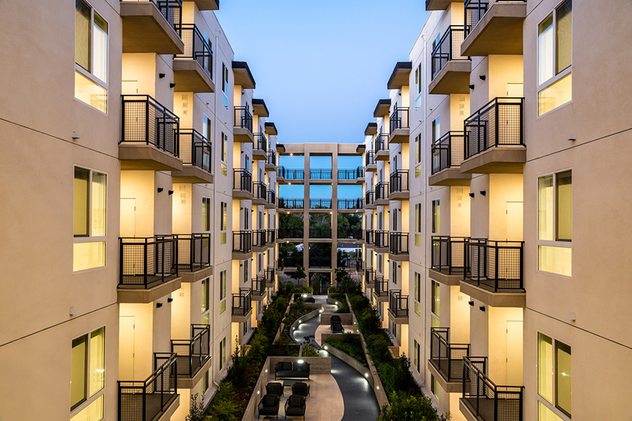 California apartment courtyard with lighted paths and landscaping overlooked by apartment balconies under twilight sky.