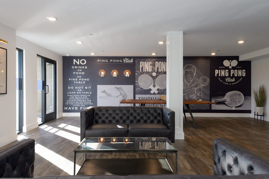 community room with black leather couches in front of a vintage black and white ping pong mural