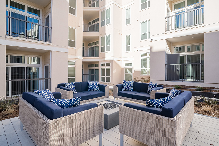 Outdoor lounge with landscaping, stone pavers, firepit, and comfortable outdoor furniture.