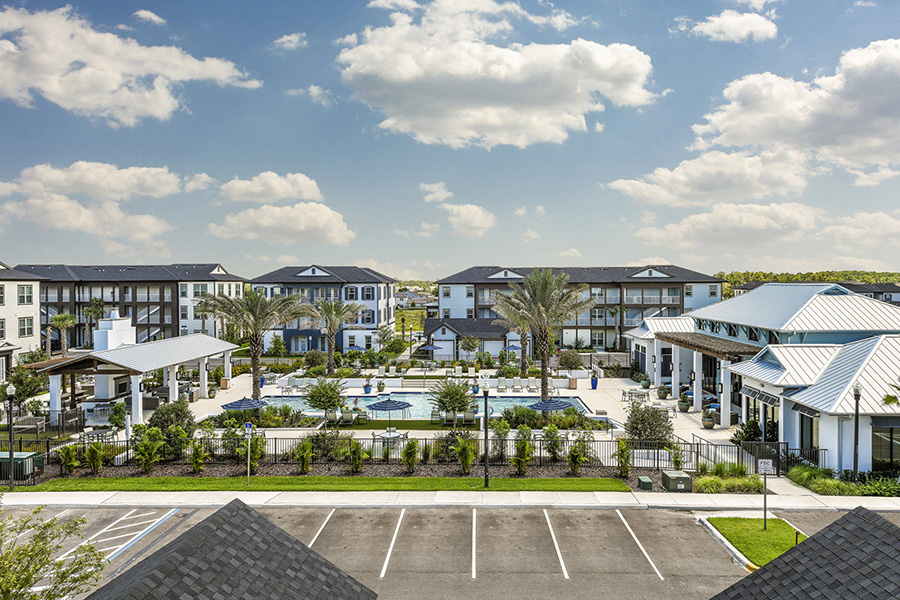IMT Sonoma Hills apartment buildings surrounding pool area under blue skies with fluffy white clouds.