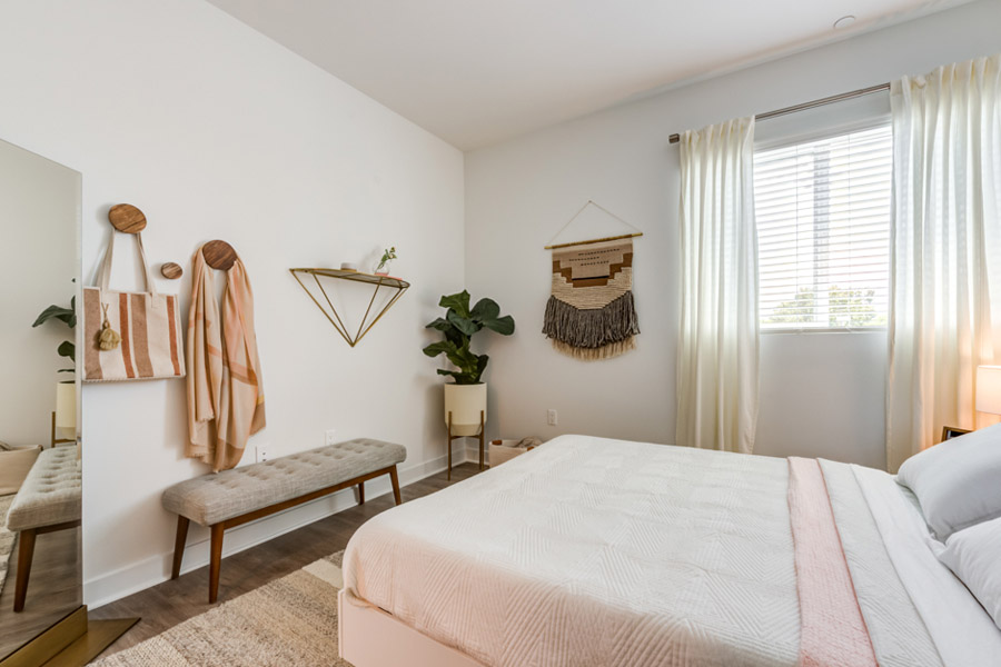 modern apartment room with pink cream bedding and scarf and tote bag accessories hung on the wall