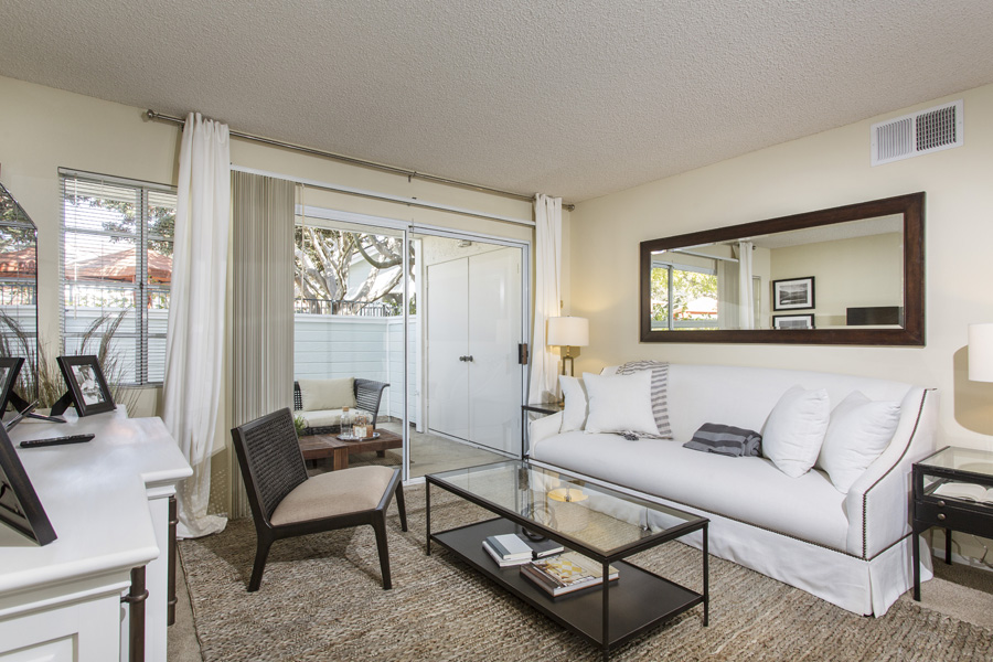 apartment living space with comfortable white couch and brown cream chair and a glass top coffee table