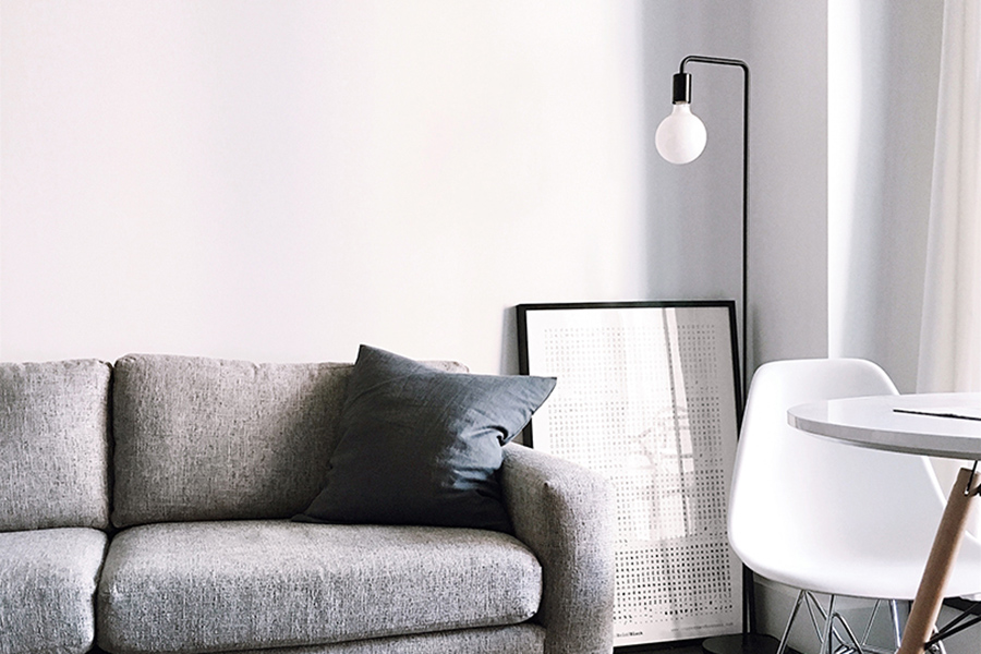 Apartment with modern white chair, comfortable plush couch, metal lamp, and natural light.