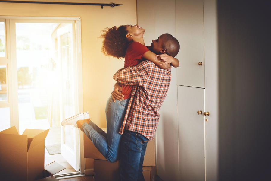 couple hugging joyfully in room with cardboard boxes stacked on floor