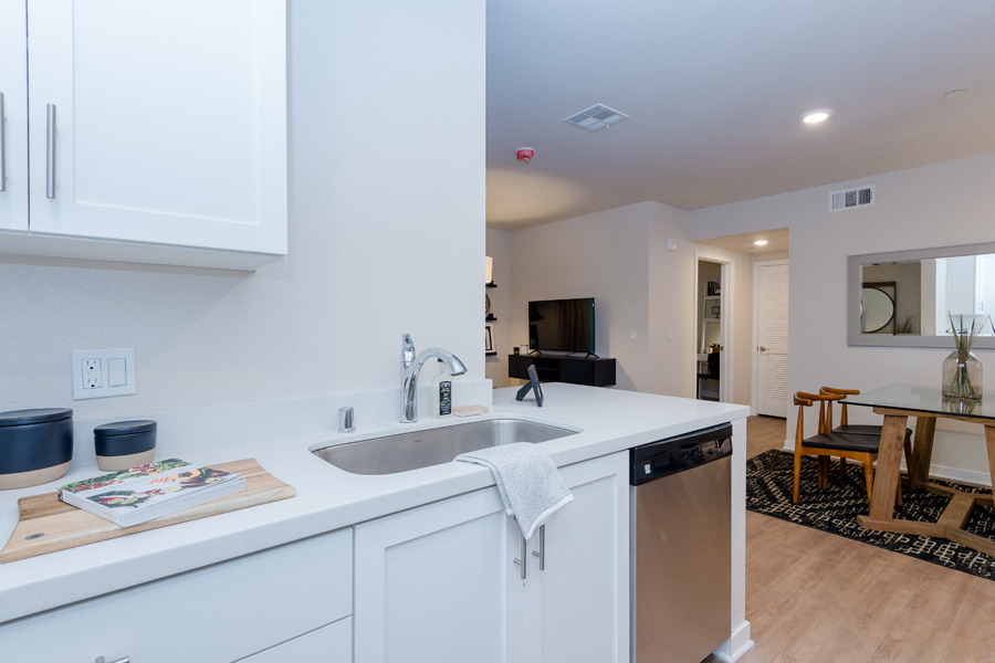 modern white apartment kitchen with stainless steel dishwasher and fresh wood flooring
