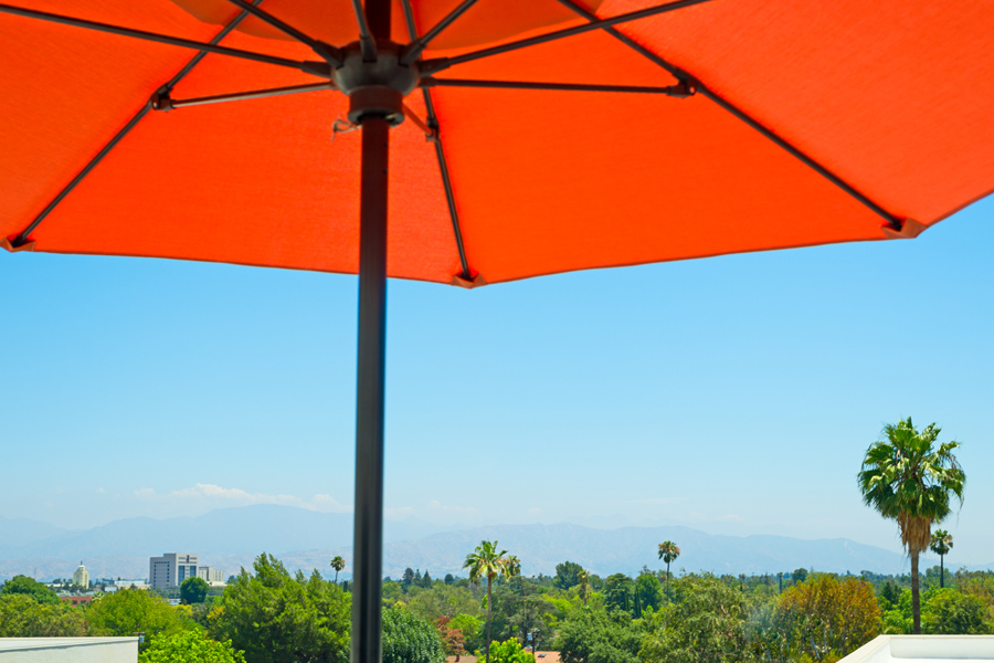 vast overview of green cityscape from underneath a bright orange umbrella and blue sky