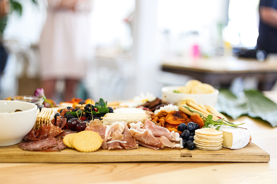 Meat and cheese board with cured meats, cheeses, crackers, and fruits.