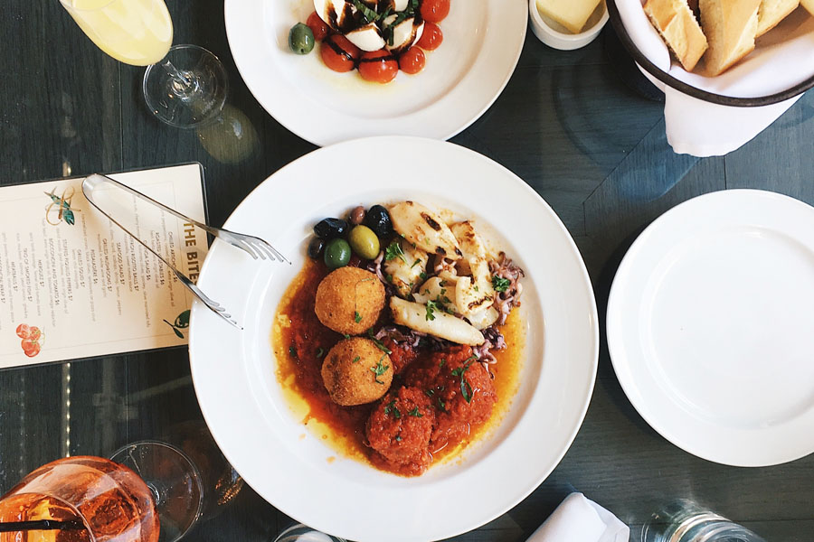 overview of a table with white plates filled with meatballs and pasta and chicken and Champagne glasses