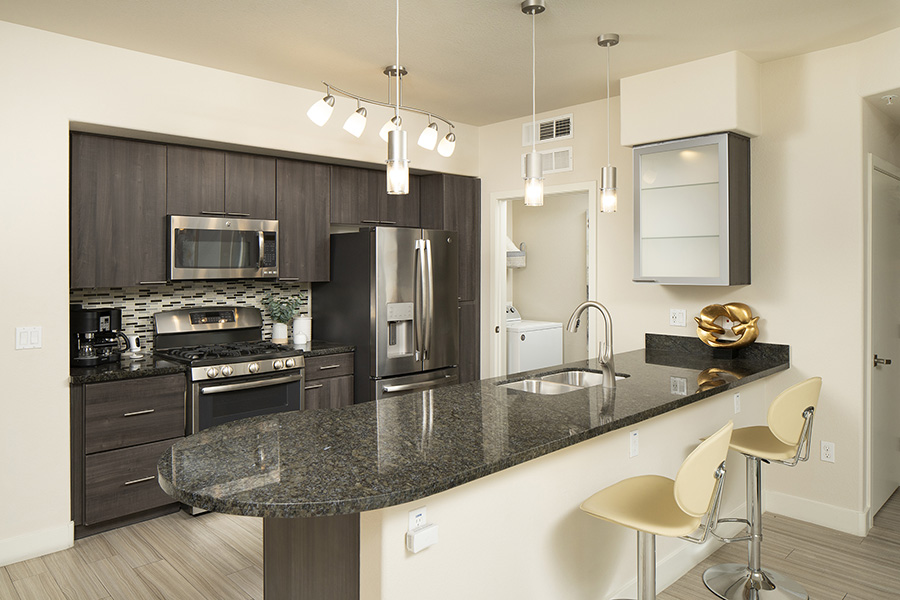 Kitchen with wood style floor and cabinets, stone counters, and stainless steel appliances.