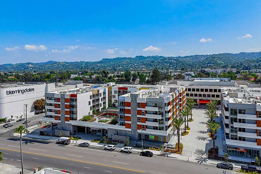Drone view of Citrus Commons mixed-use campus next to Westfield Fashion Square in Sherman Oaks, San Fernando Valley, Los Angeles, California with mountains in the background.